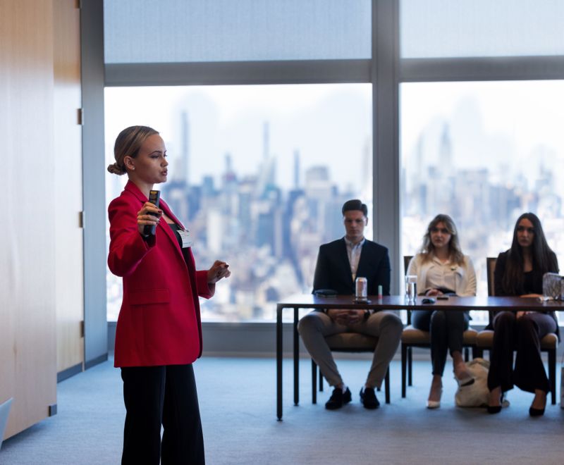 BOLD Fellowship participant delivering a pitch presentation during an entrepreneurship event with the New York City skyline in the background.